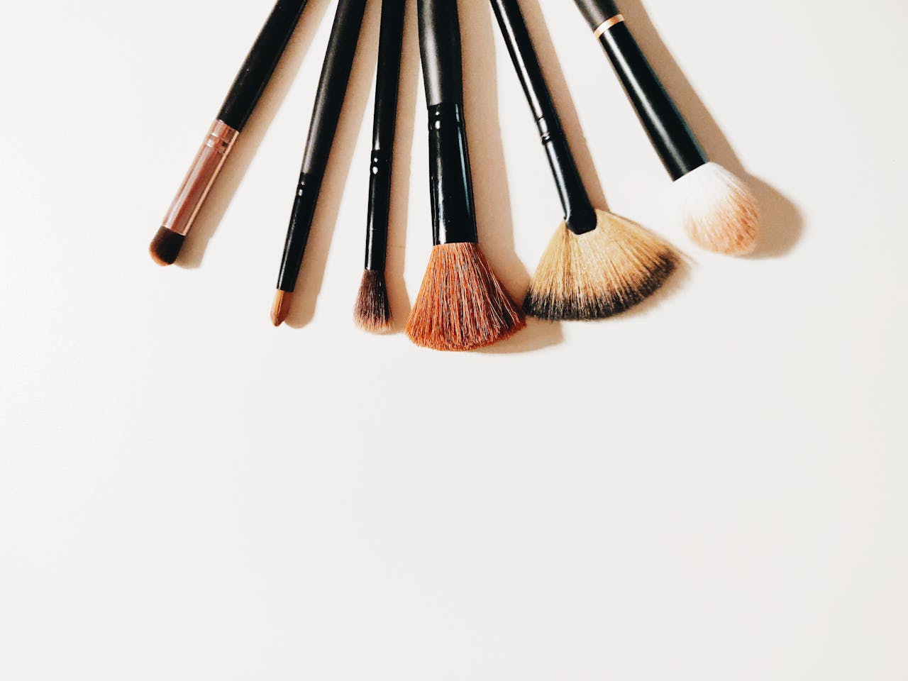 about-us A set of makeup brushes arranged on a white surface, perfect for beauty and cosmetic themes.
